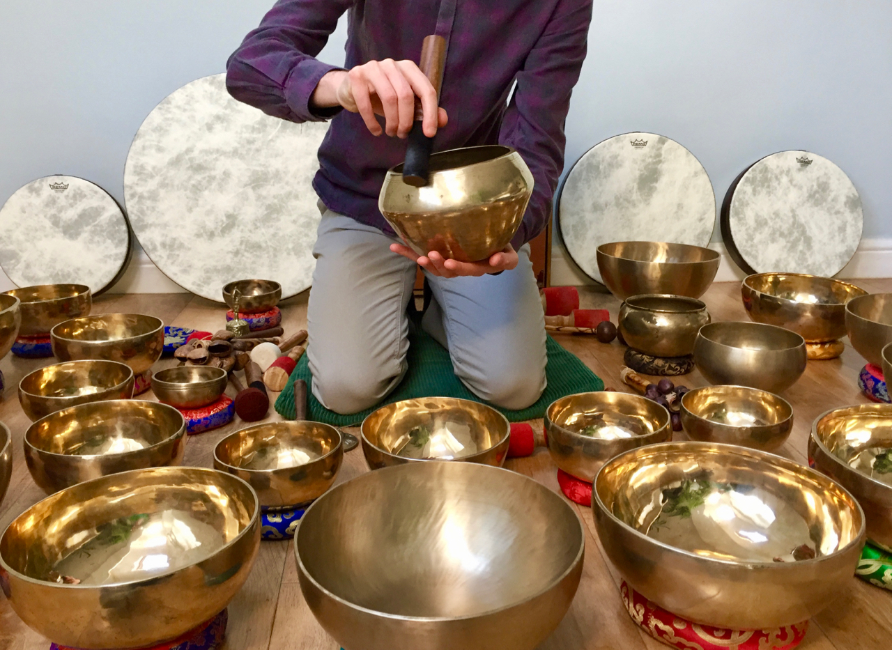 Nicholas Peters performing a sound bath with over twenty Himalayan singing bowls, frame drums, rattles and more