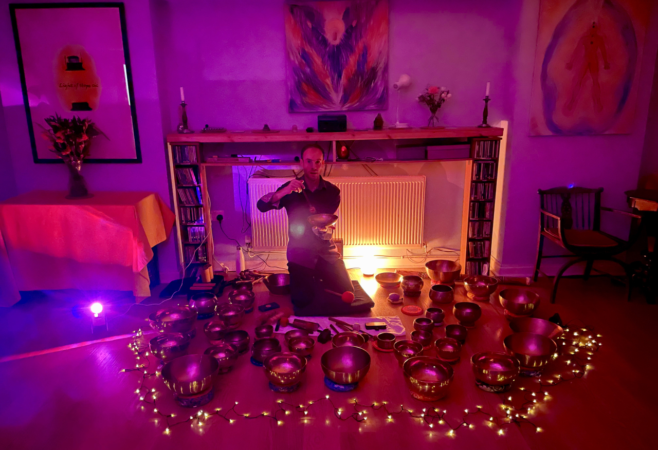Dr. Nicholas Peters playing a Manipuri Himalayan singing bowl. He is surrounded by over thirty Himalayan singing bowls.