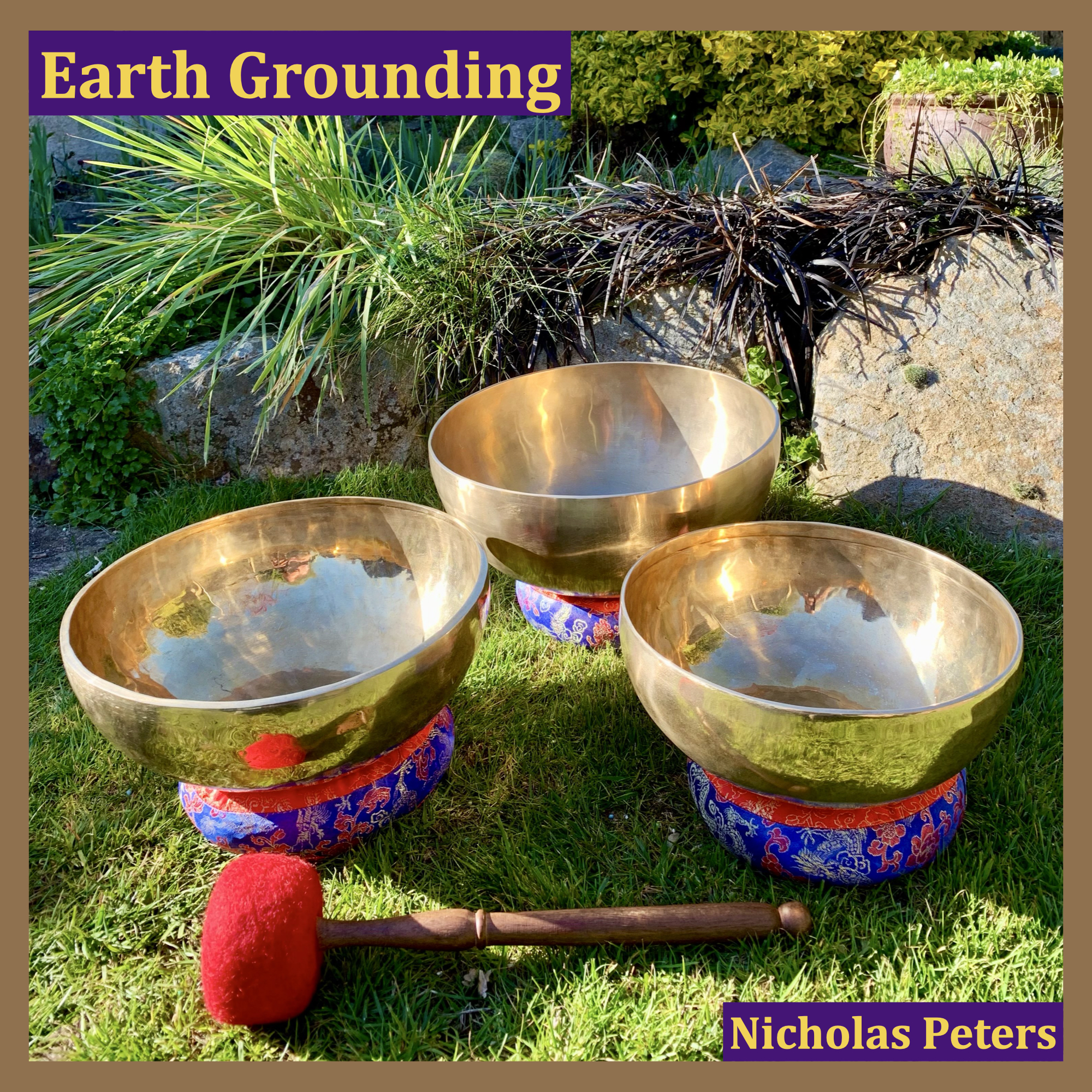 Single artwork with text that reads: “Earth Grounding by Nicholas Peters". The photograph in the artwork shows three modern Himalayan singing bowls resting on brocade cushion rings on grass with sunlight shining on them. Behind the bowls is a flower border with plants.